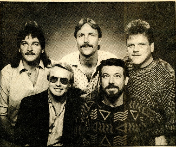 Mike Mancour with Vassar Clements outdoors, pointing at the fiddle.